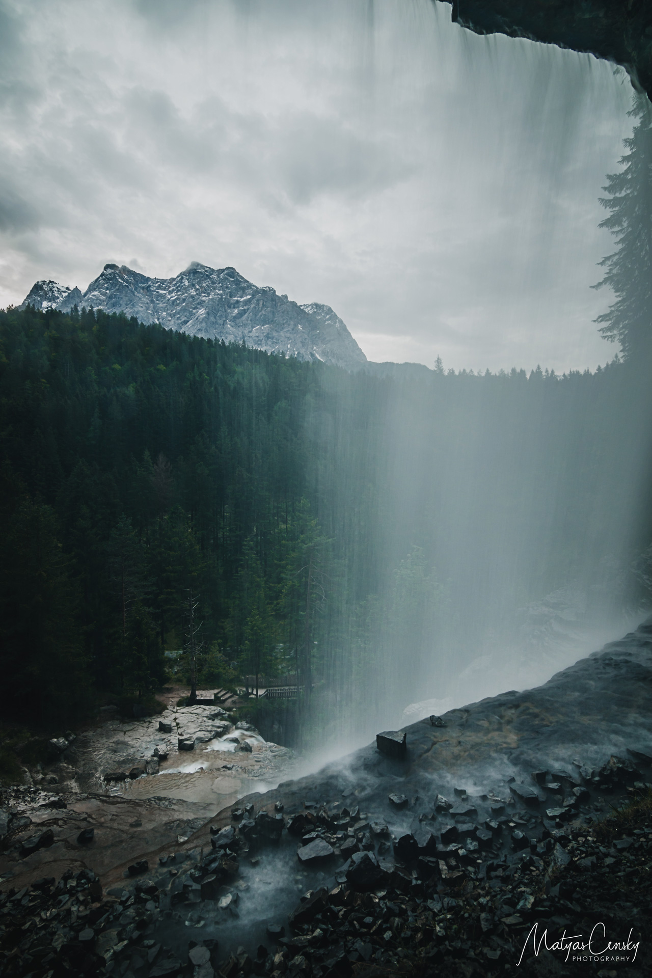 Long exposure photo of a waterfall during rain with Zugspitze in the background.