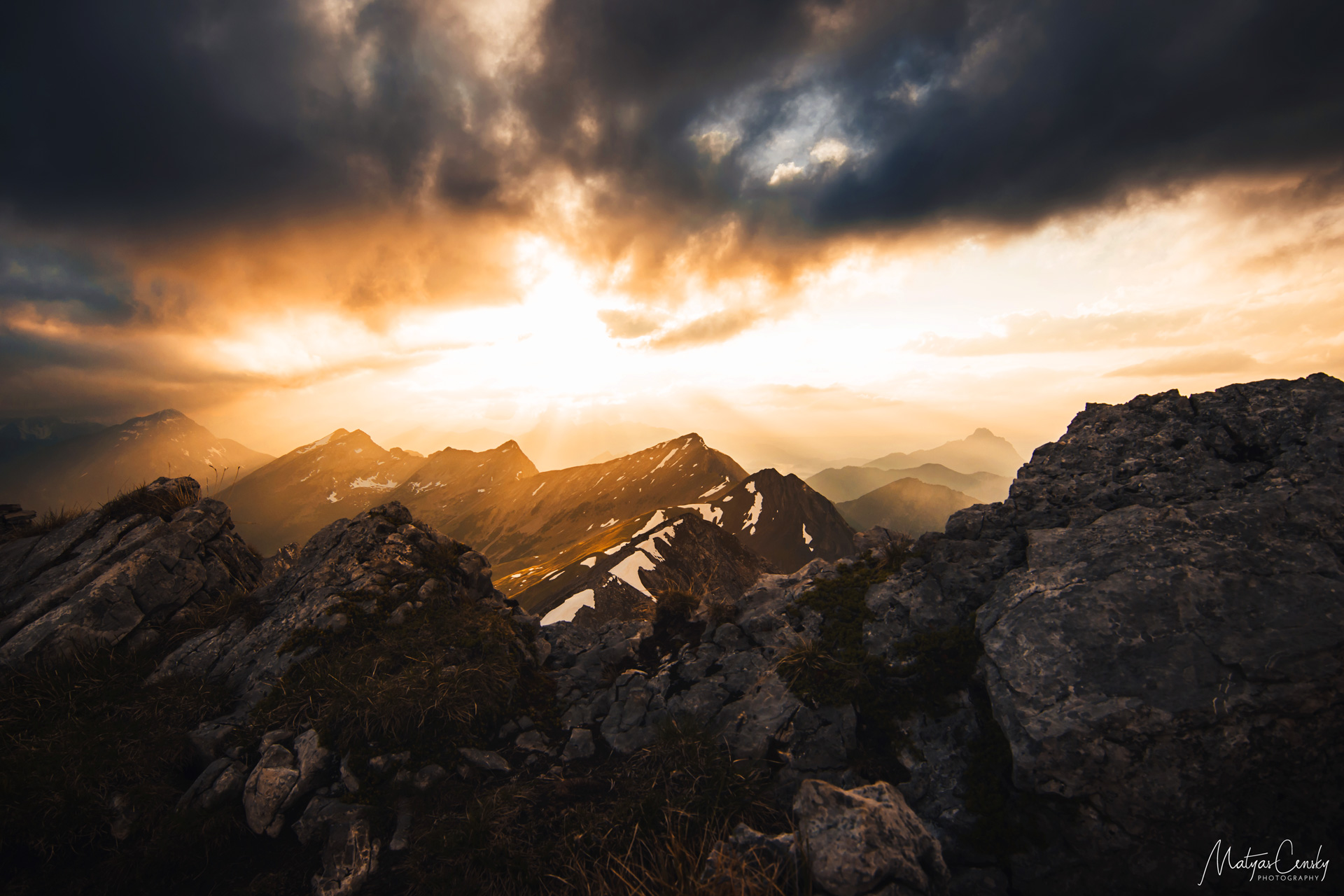 Photo of a sunset after a storm with mountain tops in the backgroung and rocks in the foreground taken from the top of Ups Spitze, Austria.