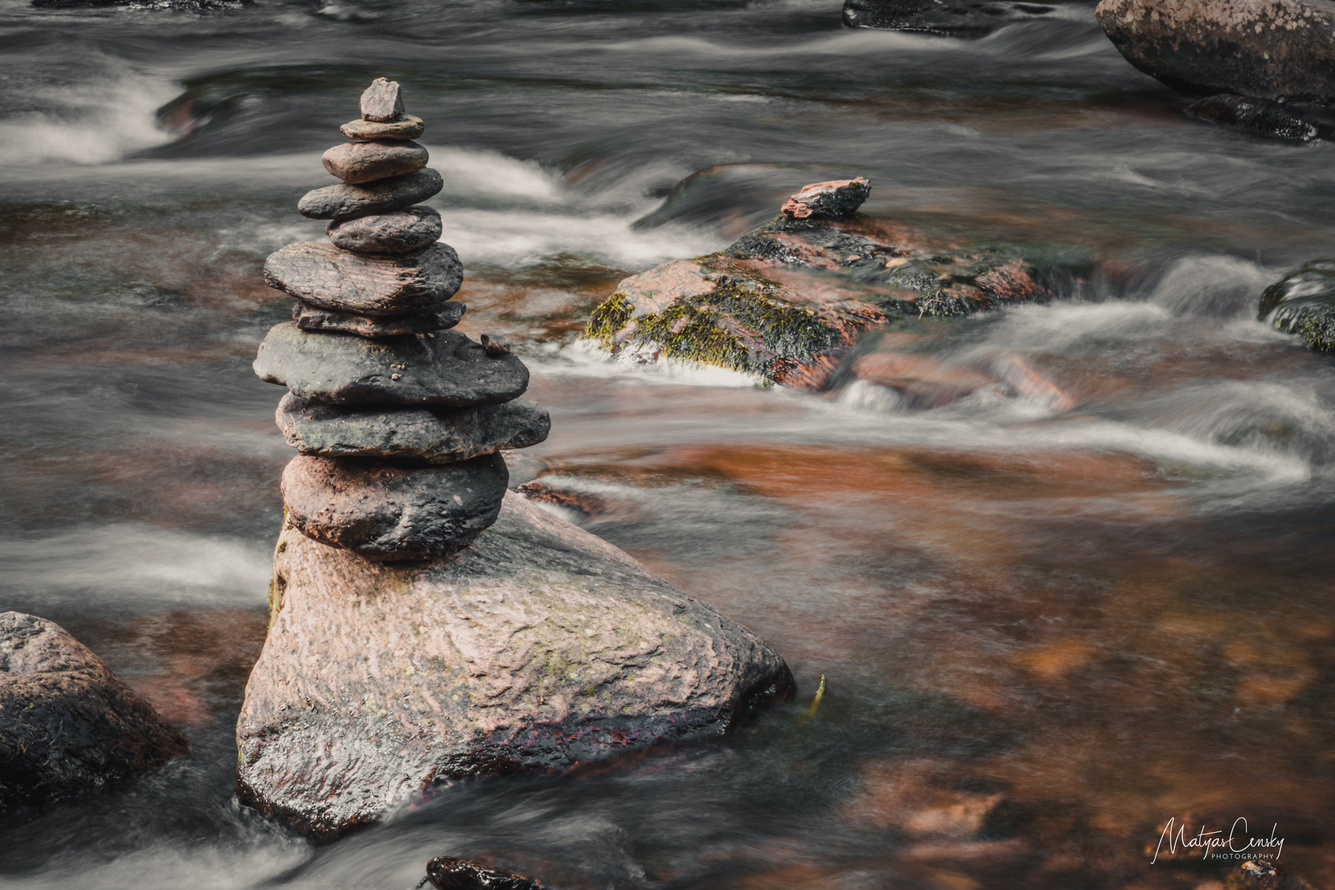 Photo of balanced stones on top of each other in the river with silky water flowing around.