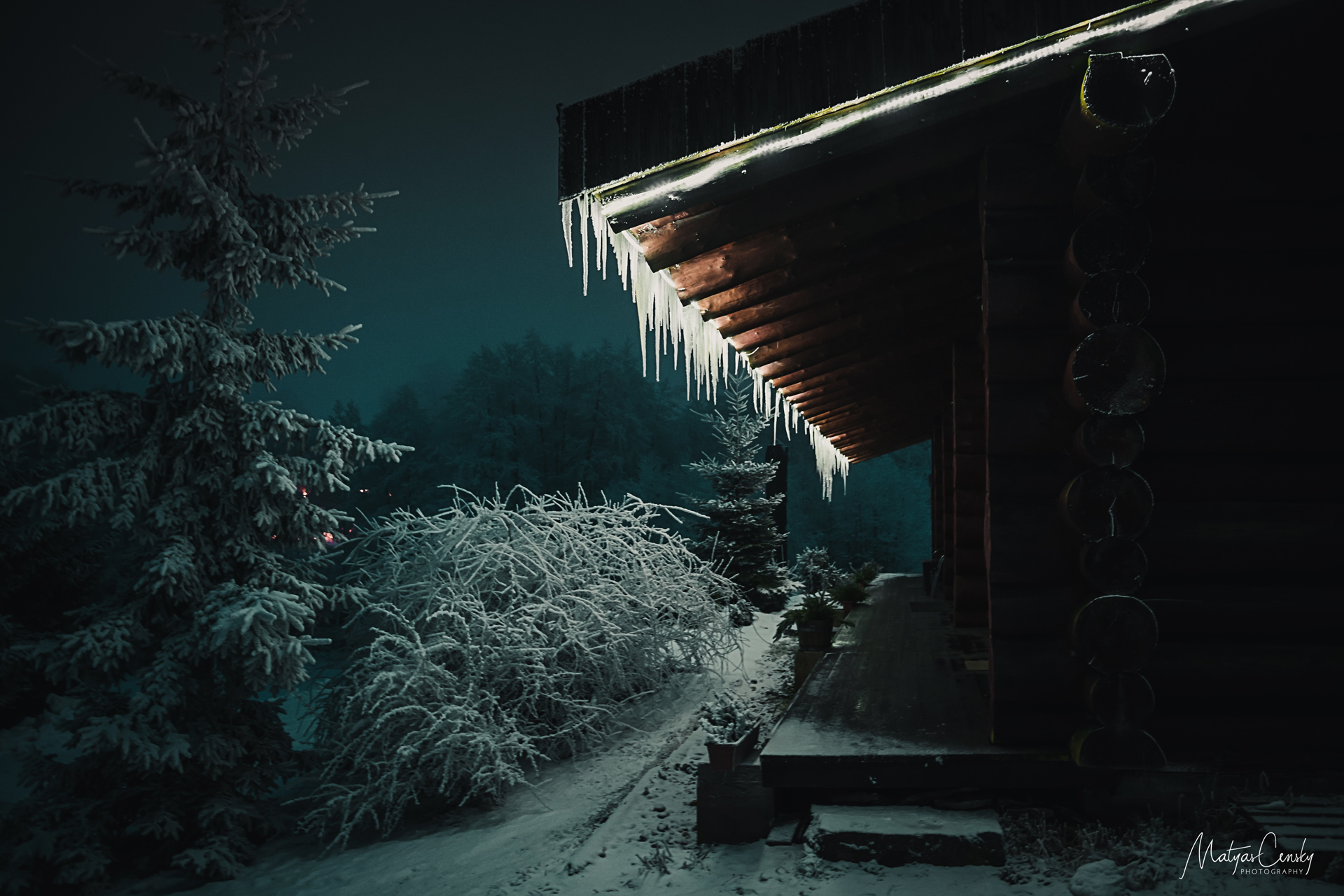 Night photo of wooden cabin in winter with bright icicle in mountains in Orlicke hory, Czech republic.