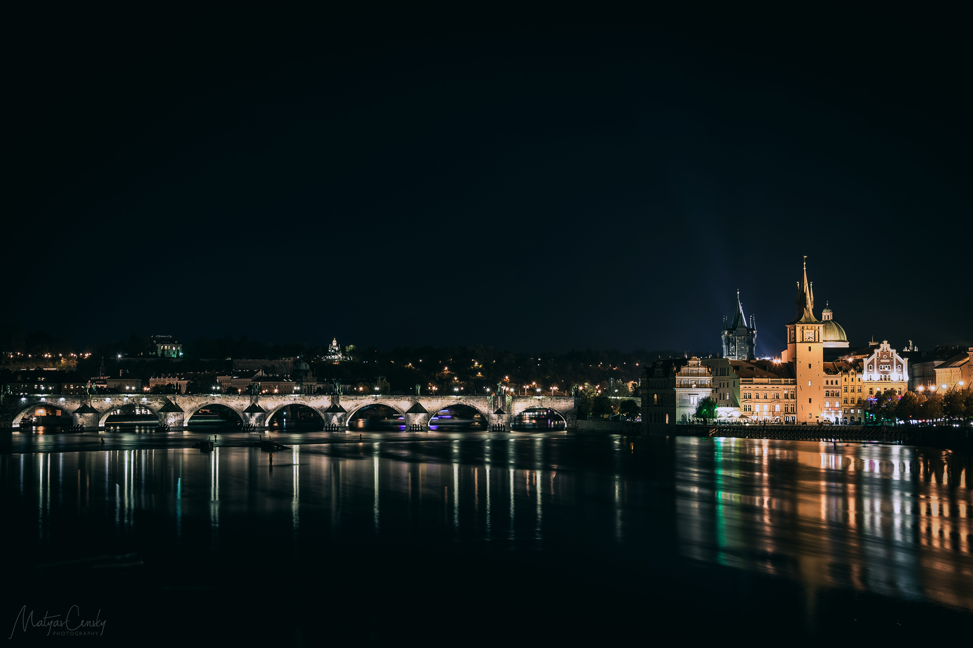 Long exposure photo of famous Charles Bridge in Prague during night with silky looking water of river Vltava.