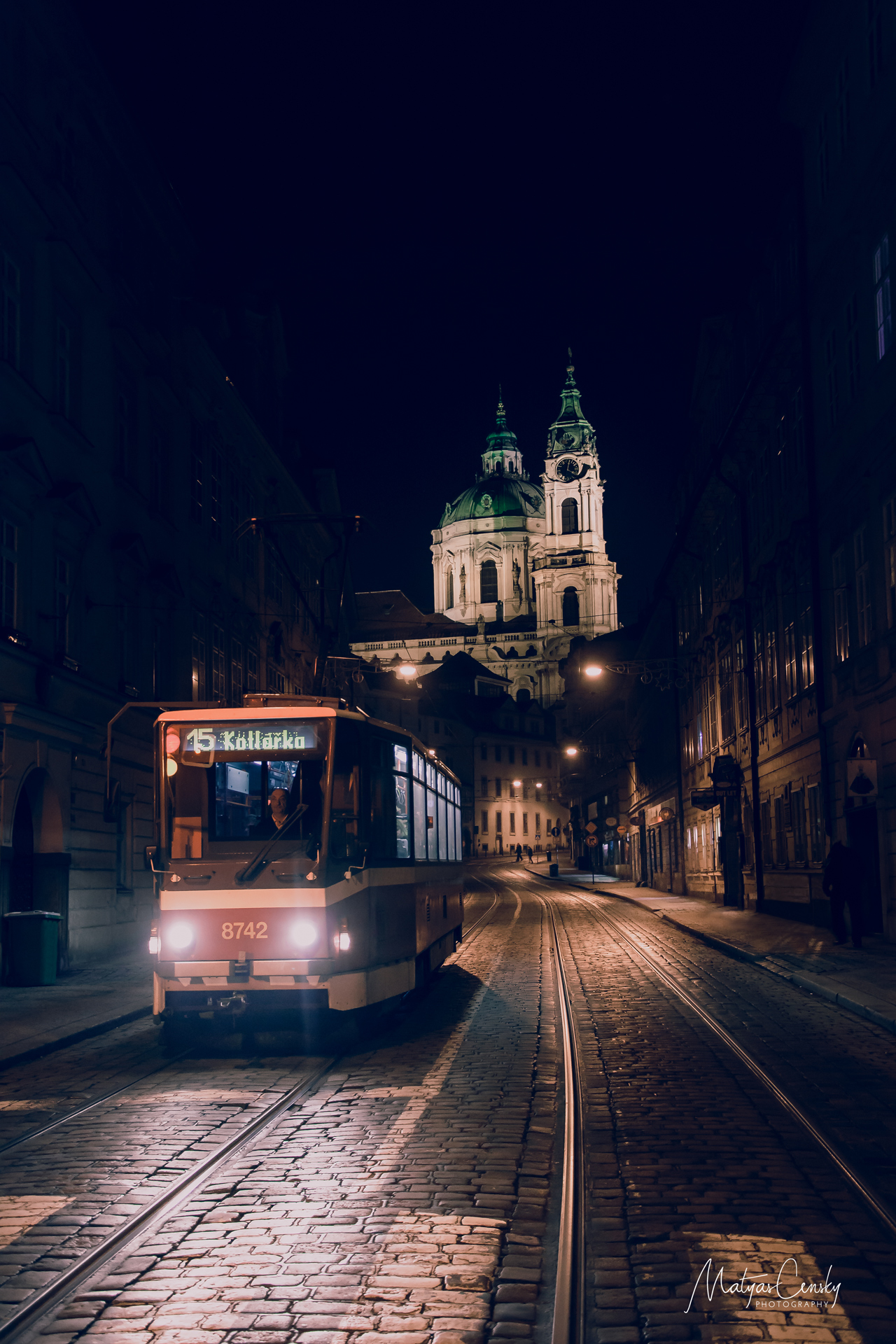 Photo of night tram with St Nicholas Bell Tower in the background.