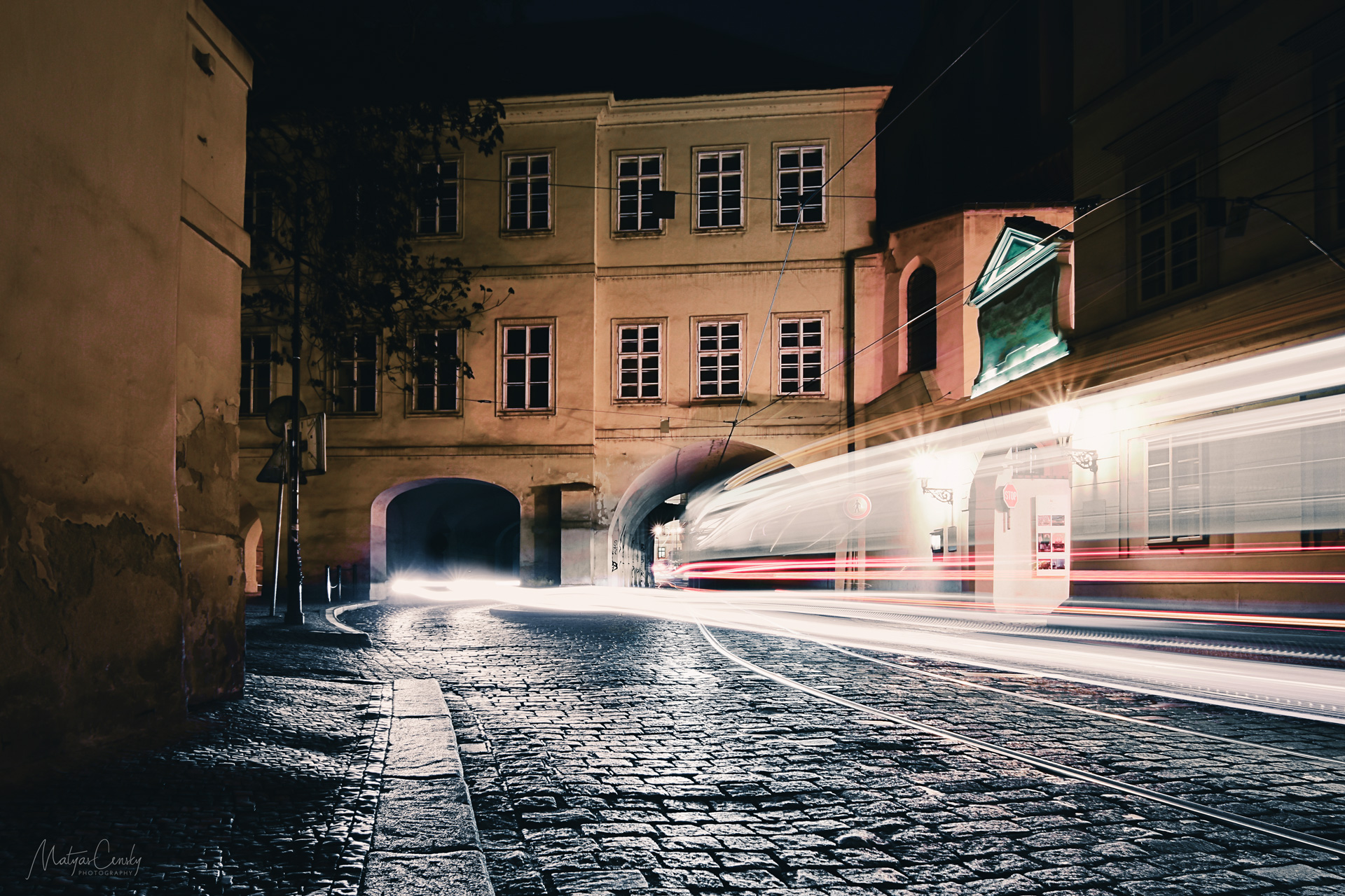 Long exposure photo of night tram and car going through a tunnels leading to Malostranske namesti in Prague.