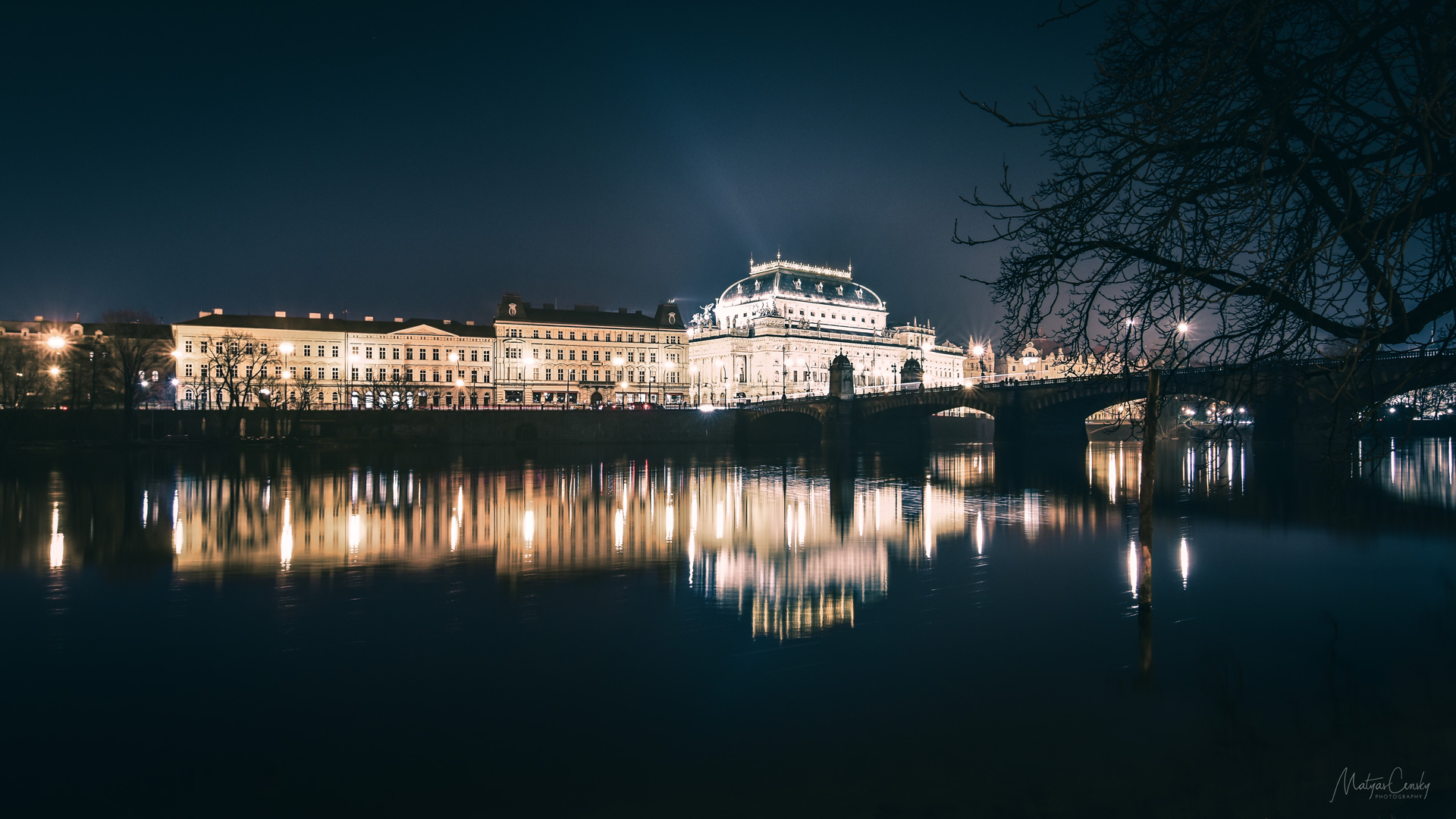 Night long exposure photo of National Theatre of Czech republic in Prague, over Vltava with silky reflection in the water.